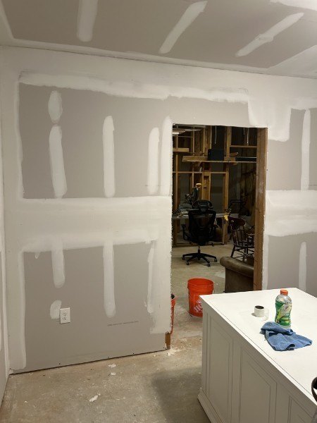 Drywall seams and screw heads coated with joint compound around a doorway