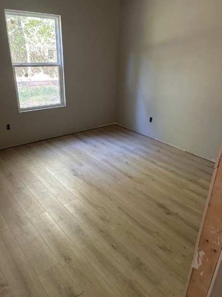 New light oak vinyl plank flooring in an empty room with a window