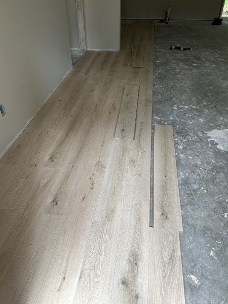 Light oak vinyl planks being laid over a concrete subfloor