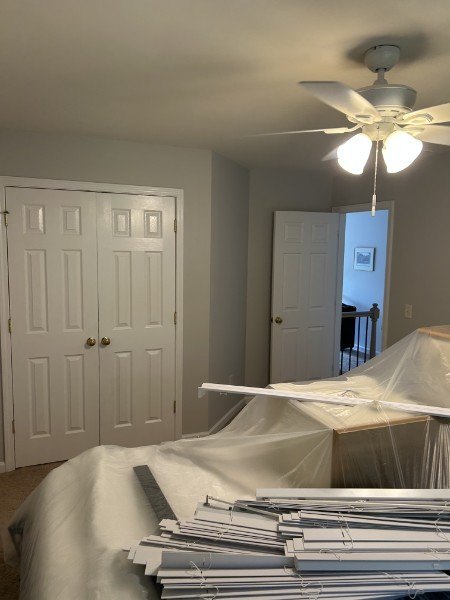 Gray bedroom with white closet doors, the window blinds taken down for painting