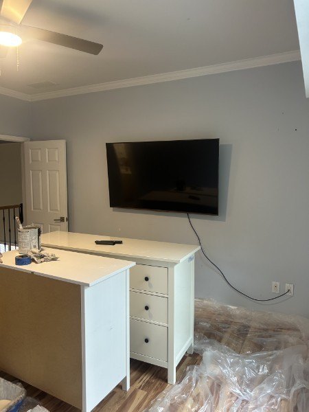 Repainted gray bedroom wall with a wall-mounted television and a white dresser
