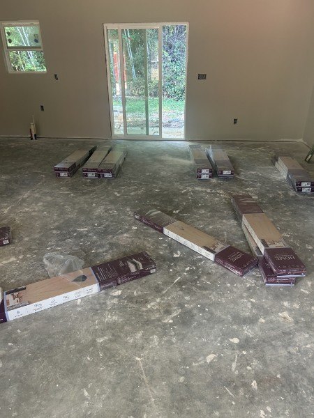 Boxes of plank flooring laid out on a bare concrete floor before installation